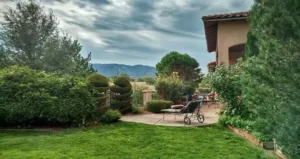 Professionally maintained residential grounds with trimmed shrubs, healthy lawn, and landscaped seating area in Albuquerque