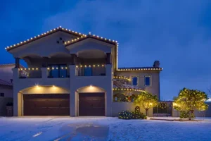 Stunning two-story home with professional holiday light installation in Albuquerque, featuring elegant warm white lights on the roofline and trees.